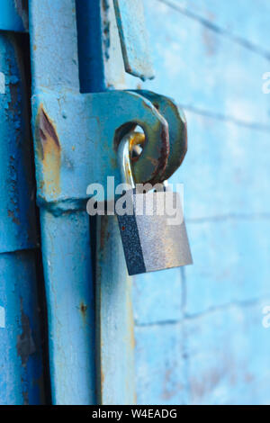 Alte Schloss auf einem blauen Metalltür mit Holzbohlen Risse im Lack und Rost Stockfoto