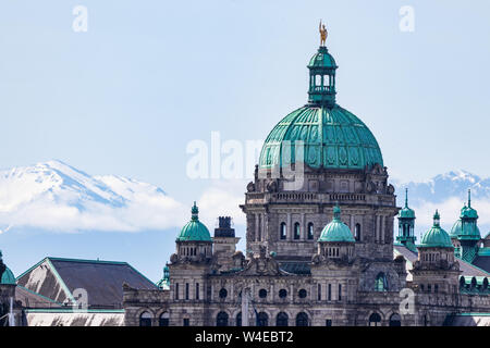 Legislative Assembly of British Columbia Gebäude an einem sonnigen Tag in Victoria, BC mit schneebedeckten Bergen im Hintergrund. Stockfoto