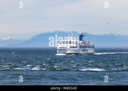 BC Ferries Schiff auf dem Meer in der Nähe von Vancouver, BC mit dem Festland Bergen im Hintergrund. Stockfoto