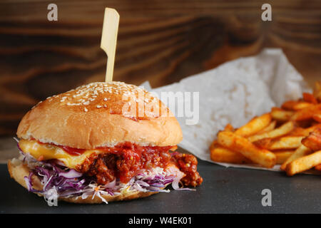 Burger mit Krautsalat und Käse auf Holz und Pommes. authentische hausgemachte Burger mit. Stockfoto