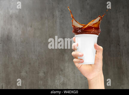 Hand mit einem styroporbecher mit Kaffee Spritzer auf der hölzernen Wand Hintergrund Stockfoto