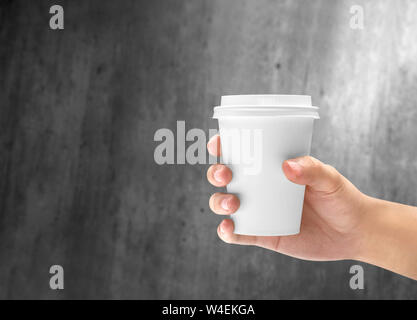 Hand mit einem Styropor Tasse heißen Kaffee auf der hölzernen Wand Hintergrund Stockfoto