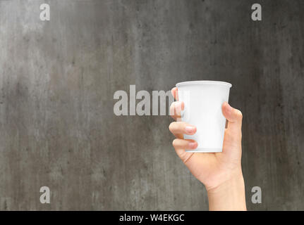 Hand mit einem styroporbecher mit Kaffee auf der hölzernen Wand Hintergrund Stockfoto