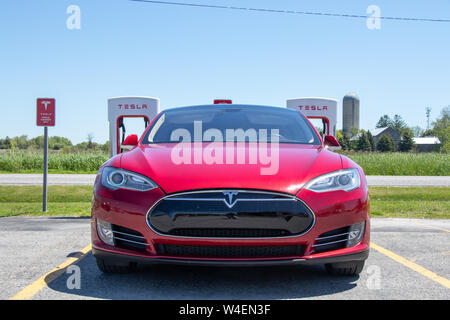 Frontansicht der Roten Tesla Model S, während sich das Fahrzeug bei Tesla Aufladung Station geparkt. Stockfoto