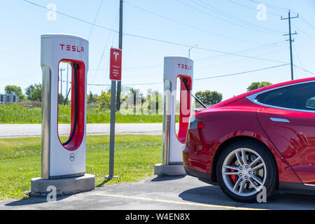 Red Tesla Model S während des Ladevorgangs bei Tesla Kompressor Station in Port Hope, Ontario gesehen. Stockfoto