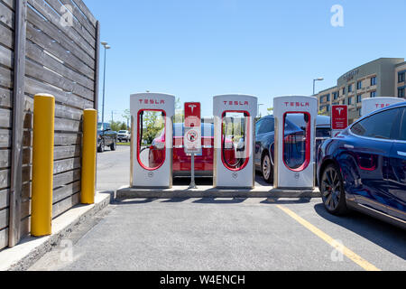 Drei Tesla Aufladung Stationen mit Blaue Modell S Laden vor und Rot und Blau Model S Modell X Plug-in-hinter sich. Stockfoto