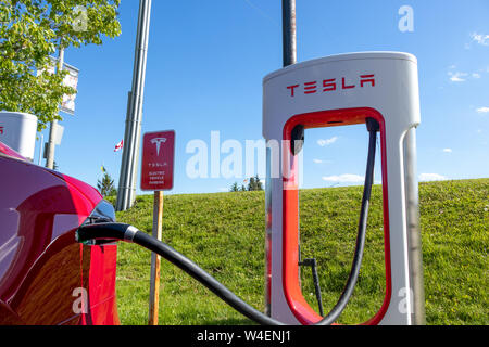 Tesla Kompressor Station und Tesla Elektroautos mit Fahrzeug gesteckten, auf einer klaren sonnigen Tag. Stockfoto