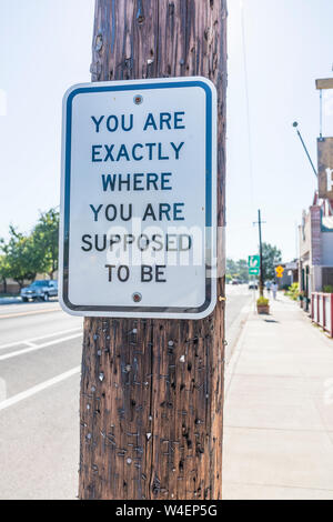 Ein lustiges Schild mit anquirky Nachricht auf einen Telefonmast, die lautet: "Sie sind genau dort, wo sie sein sollen auf dem Bürgersteig auf Bell Street in Los Stockfoto