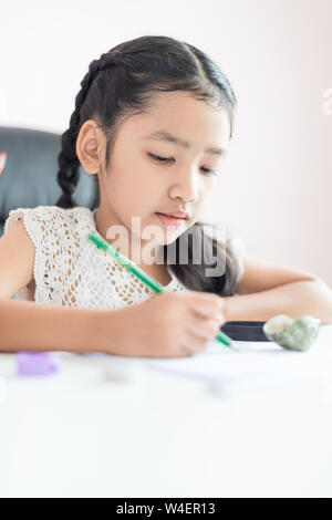 Wenig asiatisches Mädchen mit dem Bleistift auf das Papier Hausaufgaben für Bildung Konzept wählen Sie Fokus flache Tiefenschärfe zu schreiben Stockfoto