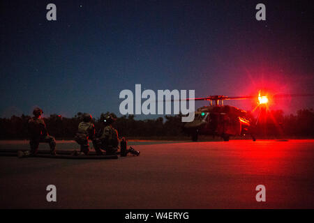 Air Commandos aus den USA 353 Special Operations Group und Australische Soldaten vom 6 Aviation Regiment vorbereiten Zum heißen Tanken eine Australische S-70A-9 Black Hawk im vorderen Bereich tanken Punkt (KASSENAERZTE) während der Talisman Sabre, 13. Juli 2019. Talisman Säbel ist eine bilaterale Übung, dass Tests die beiden Kräfte Combat Training, Bereitschaft und Interoperabilität. (U.S. Marine Corps Fotos von Lance Cpl. Nicole Rogge) Stockfoto