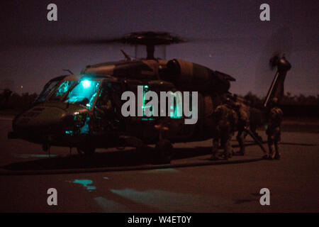 Air Commandos aus den USA 353 Special Operations Group und Australische Soldaten vom 6 Aviation Regiment heißen Tanken eine Australische S-70A-9 Black Hawk im vorderen Bereich tanken Punkt (KASSENAERZTE) während der Talisman Sabre, 13. Juli 2019. Talisman Säbel ist eine bilaterale Übung, dass Tests die beiden Kräfte Combat Training, Bereitschaft und Interoperabilität. (U.S. Marine Corps Fotos von Lance Cpl. Nicole Rogge) Stockfoto