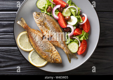 Gebratene Salema porgy Meer Fisch mit frischem Gemüse Salat close-up auf einem Teller. horizontal oben Ansicht von oben Stockfoto