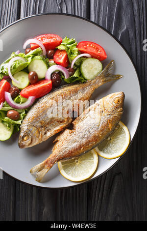 Gebratene Salema porgy Meer Fisch mit frischem Gemüse Salat close-up auf einem Teller. Vertikal oben Ansicht von oben Stockfoto