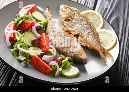 Natürliches gesundes essen gebratene Salema porgy Fisch mit Zitrone und frischen Salat close-up auf einem Teller auf den Tisch. Horizontale Stockfoto