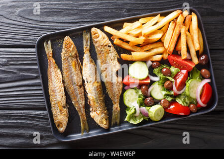 Frisch gebratenen boops boops Fisch mit Sommer Gemüse Salat und Pommes frites Close-up auf einem Teller auf den Tisch. horizontal oben Ansicht von oben Stockfoto