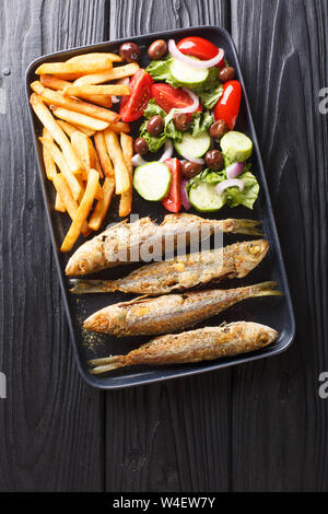 Frisch gebratenen boops boops Fisch mit Sommer Gemüse Salat und Pommes frites Close-up auf einem Teller auf den Tisch. Vertikal oben Ansicht von oben Stockfoto