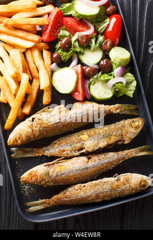Gebratene boops boops Fisch mit frischem Gemüse Salat und Pommes frites Close-up auf einem Teller auf den Tisch. Vertikal oben Ansicht von oben Stockfoto