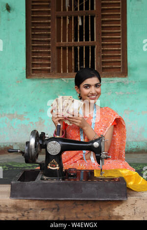 Frau mit Nähmaschine und Geld zählen Stockfoto