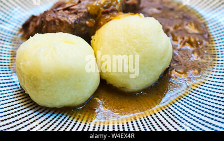 Typisch deutsche Knödel, halb Roh und Halb gekochten Kartoffeln, auf einem Sauerbraten mit Brauner Soße Stockfoto