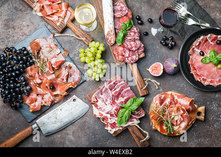 Verschiedene Arten jamon auf Schneiden boardes mit Feigen, Trauben und Wein. Parmaschinken, hamon auf hölzernen Hintergrund mit Kopie Raum, Ansicht von oben. Stockfoto