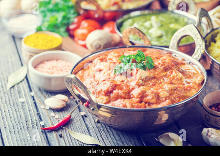 Verschiedene Schalen mit sortierten indischen Essen auf dunklem Hintergrund. Huhn, Curry Reis, Linsen, Paneer, chapati und Gewürzen. Stockfoto