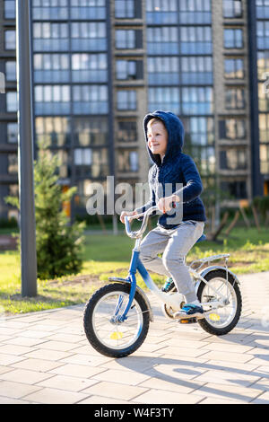 Sicherheit in einer modernen europäischen Stadt. Ein wenig glückliche junge fährt mit dem Fahrrad durch einen geschlossenen Innenhof in einem Mehrstöckigen städtischen Gebäude. Stockfoto