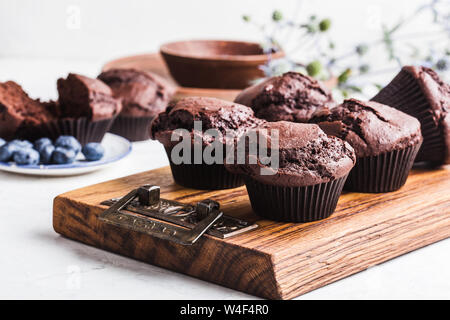 Hausgemachte chocolate Muffins und frische Blaubeeren auf Holz Schneidebrett, Nahaufnahme, leckeres Dessert oder Frühstück Stockfoto