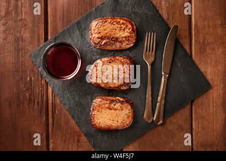 Sirloin Rindersteaks und Rotwein, geschossen von oben auf einem schwarzen Schiefer Platte Stockfoto
