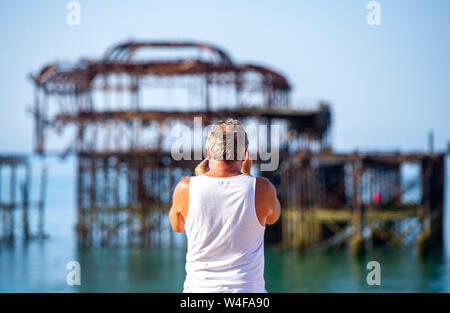 Brighton UK 23. Juli 2019 - die Besucher am frühen Morgen heißen Sonne genießen von der West Pier in Brighton. Hitzewelle Bedingungen sind für den Südosten von Großbritannien mit Temperaturen erwartet, die Mitte der 30er Jahre heute zu erreichen und in den nächsten Tagen erwartet. Foto: Simon Dack/Alamy leben Nachrichten Stockfoto