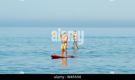 Brighton UK 23. Juli 2019 - Paddel Boarder genießen Sie die warme Sonne am frühen Morgen von der West Pier in Brighton. Hitzewelle Bedingungen sind für den Südosten von Großbritannien mit Temperaturen erwartet, die Mitte der 30er Jahre heute zu erreichen und in den nächsten Tagen erwartet. Foto: Simon Dack/Alamy leben Nachrichten Stockfoto