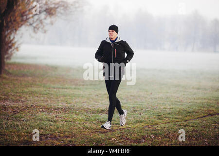 Winter Runner. Mann im Park am kalten Morgen läuft. Stockfoto