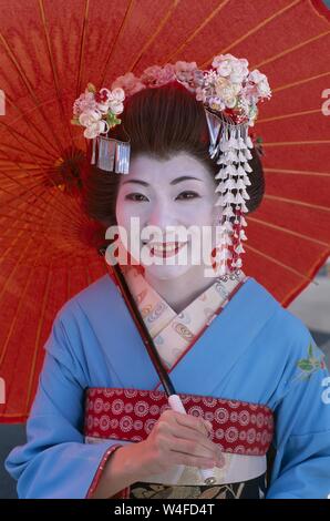 Japan, Honshu, Kyoto, Gion Distrikt, Mädchen gekleidet als Geisha Kimono Tragen und Halten roten Papier Regenschirm Stockfoto