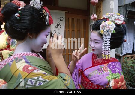 Japan, Honshu, Kyoto, Gion Distrikt, zwei Mädchen gekleidet als Geisha Kimono tragen, Aufnehmen von Fotos Stockfoto