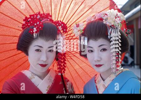 Japan, Honshu, Kyoto, Gion Distrikt, Mädchen gekleidet als Geisha Kimono Tragen und Halten roten Papier Regenschirm Stockfoto