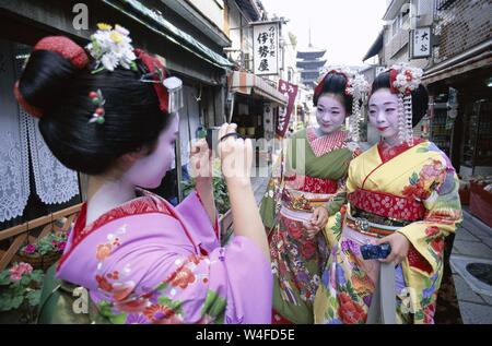 Japan, Honshu, Kyoto, Gion District, drei Mädchen gekleidet als Geisha Kimono tragen, Aufnehmen von Fotos Stockfoto
