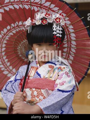 Japan, Honshu, Tokio, junges Mädchen gekleidet in traditionellen Kimono Holding Papier Sonnenschirme für den jährlichen 7-5-3 (Shichi-go-san) auf November 15. Stockfoto