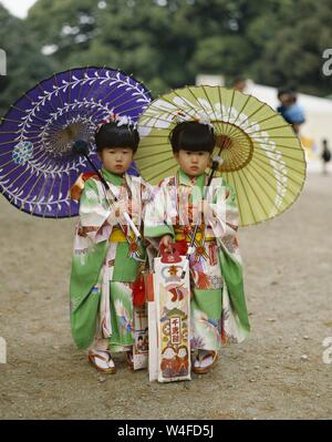 Japan, Honshu, Tokio, zwei Mädchen gekleidet in traditionellen Kimono Holding Papier Sonnenschirme für den jährlichen 7-5-3 (Shichi-go-san) auf November 15. Stockfoto