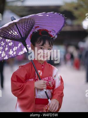 Japan, Honshu, Tokio, junges Mädchen gekleidet in traditionellen Kimono Holding Papier Sonnenschirme für den jährlichen 7-5-3 (Shichi-go-san) auf November 15. Stockfoto