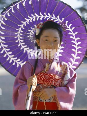 Japan, Honshu, Tokio, junges Mädchen gekleidet in traditionellen Kimono Holding Papier Sonnenschirme für den jährlichen 7-5-3 (Shichi-go-san) auf November 15. Stockfoto