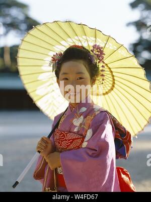 Japan, Honshu, Tokio, junges Mädchen gekleidet in traditionellen Kimono Holding Papier Sonnenschirme für den jährlichen 7-5-3 (Shichi-go-san) auf November 15. Stockfoto