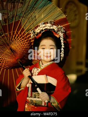 Japan, Honshu, Tokio, junges Mädchen gekleidet in traditionellen Kimono Holding Papier Sonnenschirme für den jährlichen 7-5-3 (Shichi-go-san) auf November 15. Stockfoto