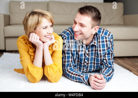Portrait von nettes Paar liegend auf dem Boden in der neuen Wohnung und an jedem anderen Suchen Stockfoto