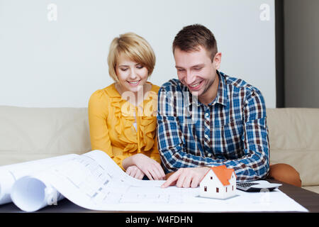 Junge glückliches Paar sitzt auf einem Sofa und Blick auf eine Blaupause Stockfoto