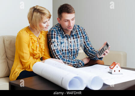 Junges Paar sitzt auf einem Sofa und die Berechnung der Bau Haushalt Stockfoto