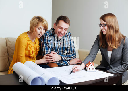 Junges Paar über die Layouts von einem zukünftigen Haus mit einem Architekten Stockfoto