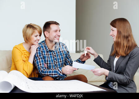 Junges Paar Erhalt der Schlüssel von einem Immobilienmakler Stockfoto