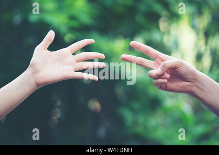 Paar spielen Rock Paper Scissors hand Spiel der Natur grüner Hintergrund Stockfoto