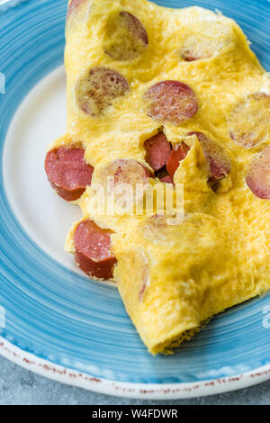 Gefaltete Omelette mit Würstchen/Salamischeiben zum Frühstück. Stockfoto