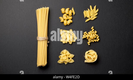 Verschiedene Arten von Pasta auf schwarzem Hintergrund. Ansicht von oben. Verschiedene Formen der Pasta. Stockfoto