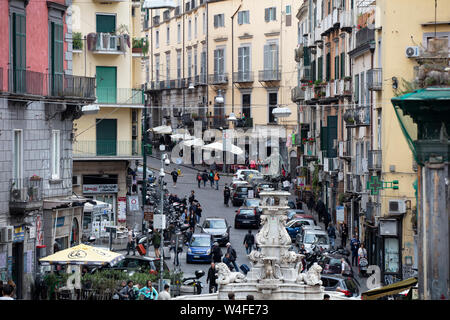 Eine typische Straßenszene in der Altstadt von Neapel mit einem barocken Statue, Menschenmassen und Verkehr. Stockfoto